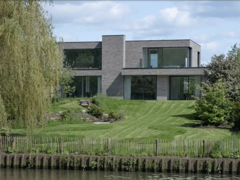 Architect Pascal Bilquin creëerde een idyllische nieuwbouw langs de Leie. De villa heeft een strakke baksteenarchitectuur met slanke gevelstenen in wildverband op een dunmortelbed.
