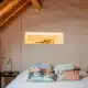 Moderne slaapkamer met golvend pleisterwerk, houten balken en ingebouwde verlichte nis in landelijke woning