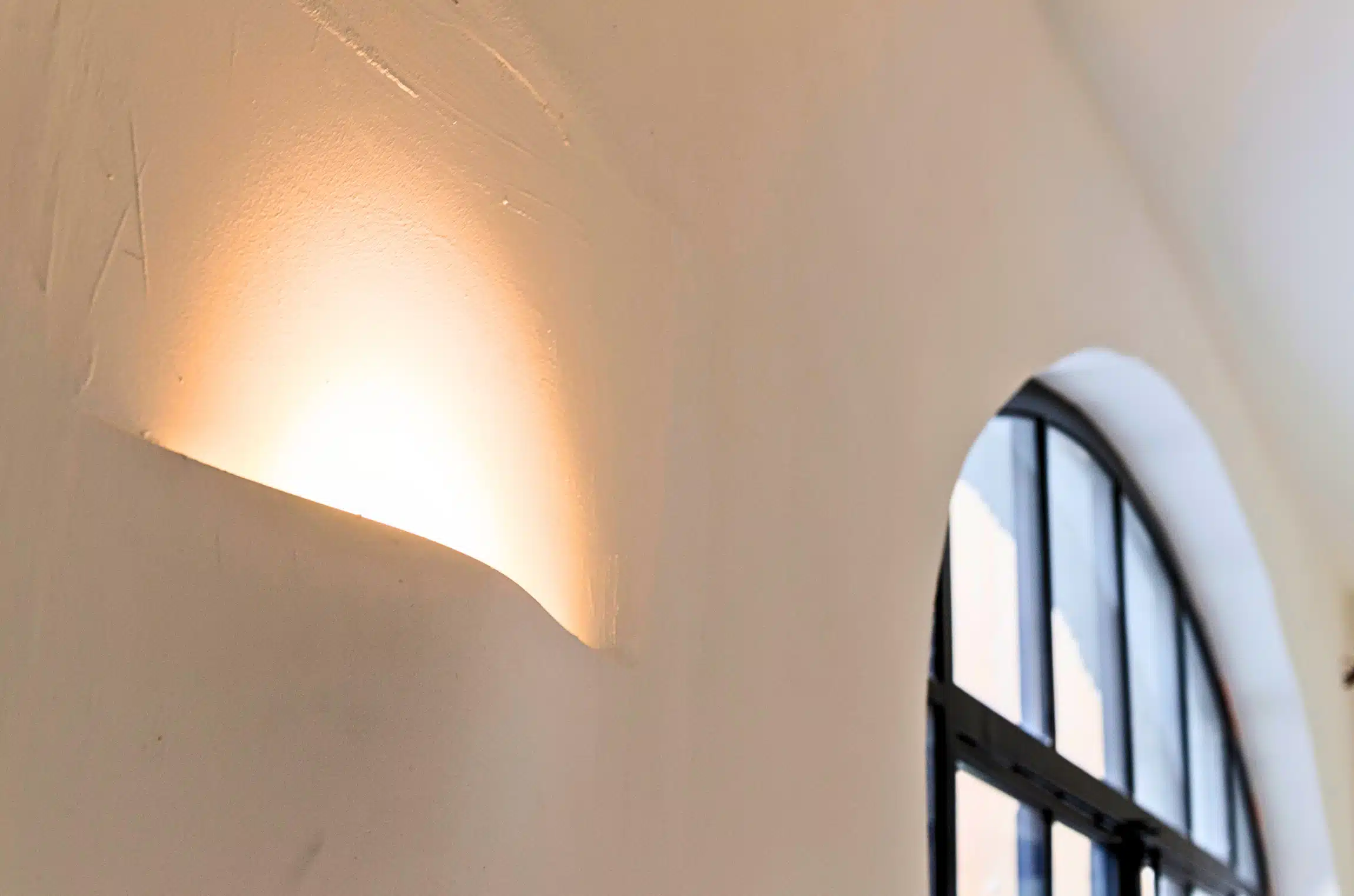 Wand met ingewerkt licht en golvend pleisterwerk - Project Zottegem