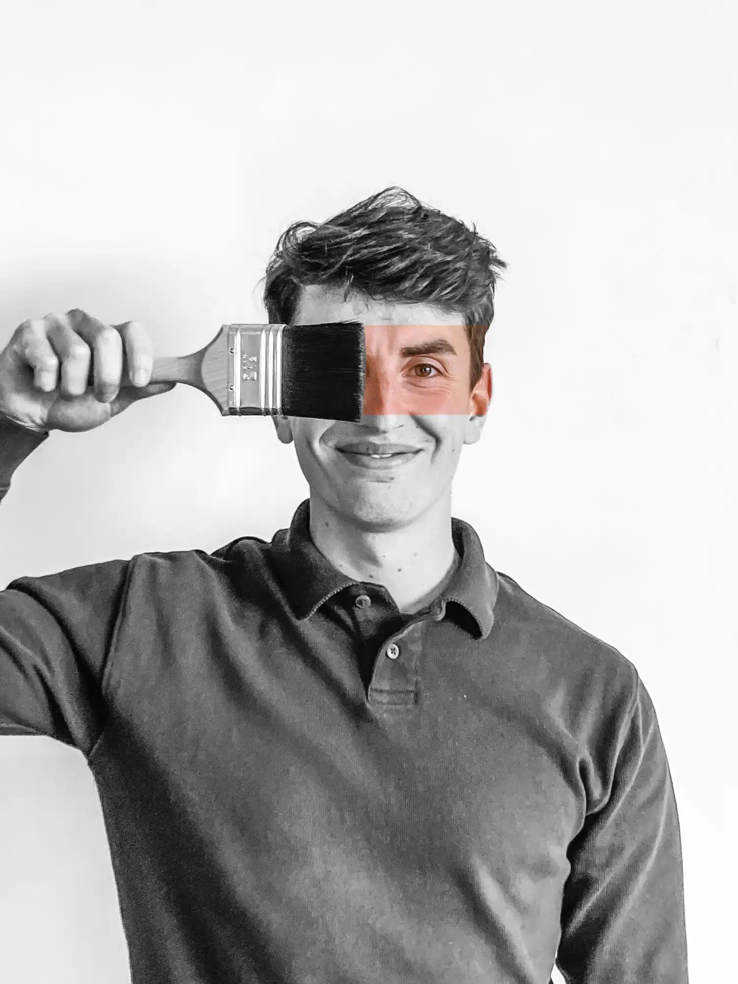 Medewerker van pleisterwerkbedrijf In't Wit houdt verfkwast voor zijn oog, zwart-wit portret