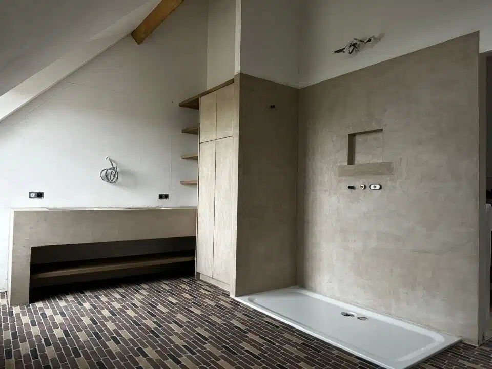 Afgewerkte badkamer in Nukerke met pleisterwerk wanden, bakstenen vloer, inloopdouche en houten kastenwand — pleisterwerken d